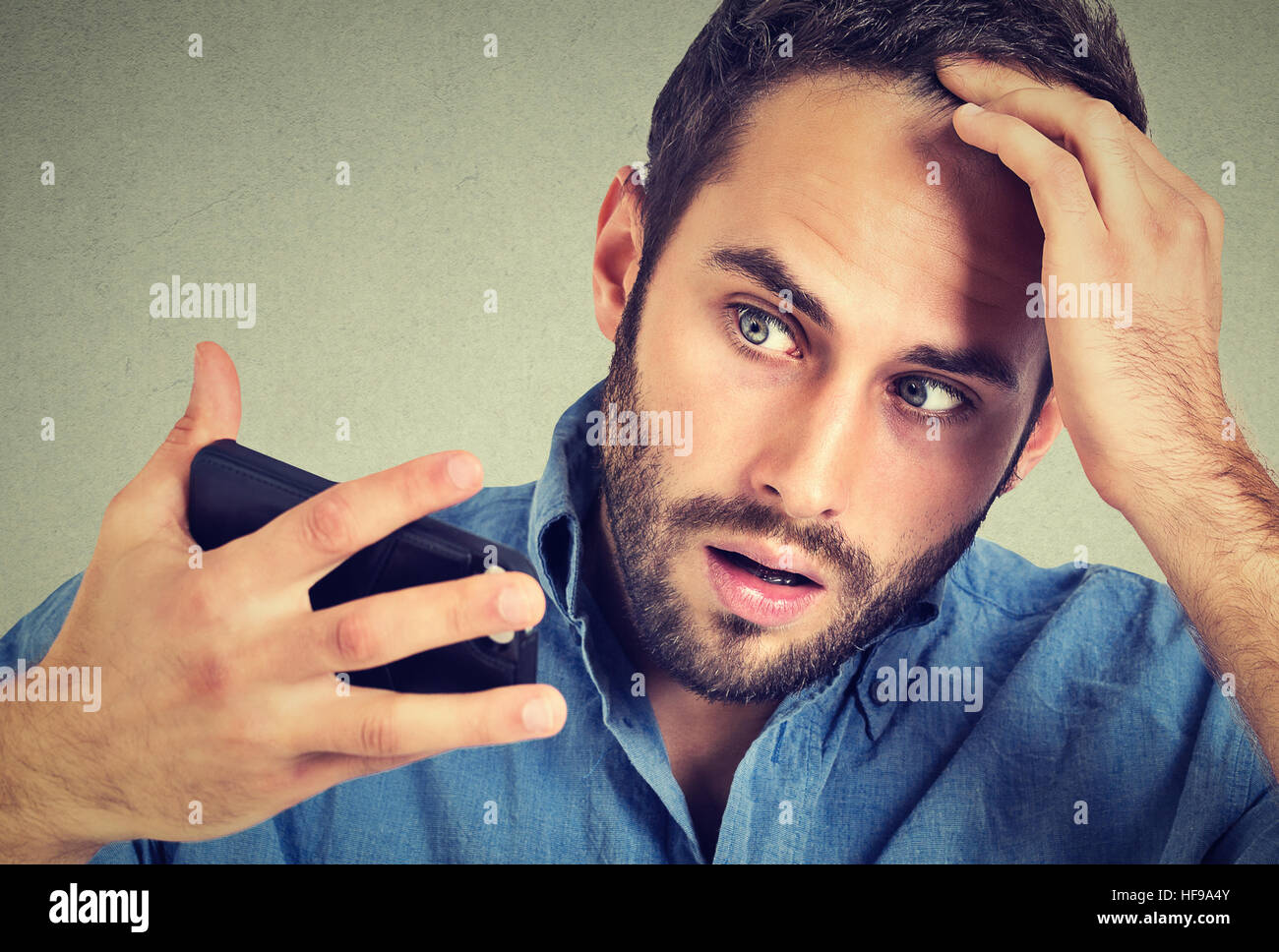 Preoccupied shocked man feeling head, surprised he is losing hair, receding hairline, bad news isolated on gray background. Negative facial expression Stock Photo