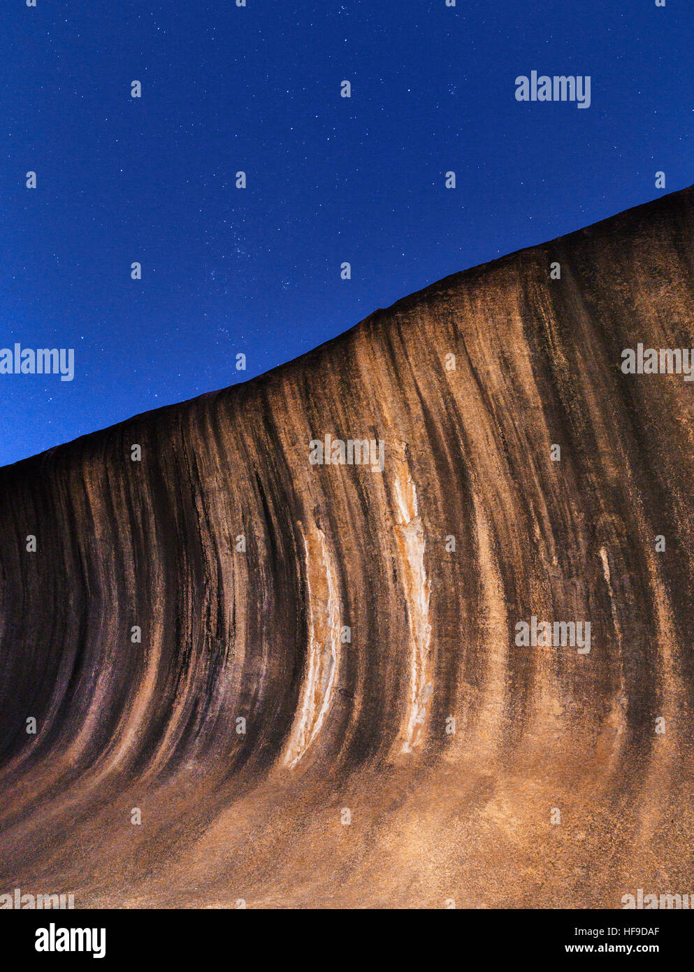 The flared slope of Wave Rock under the stars at night. Western Australia. The black stripes are caused by algae discoloration Stock Photo