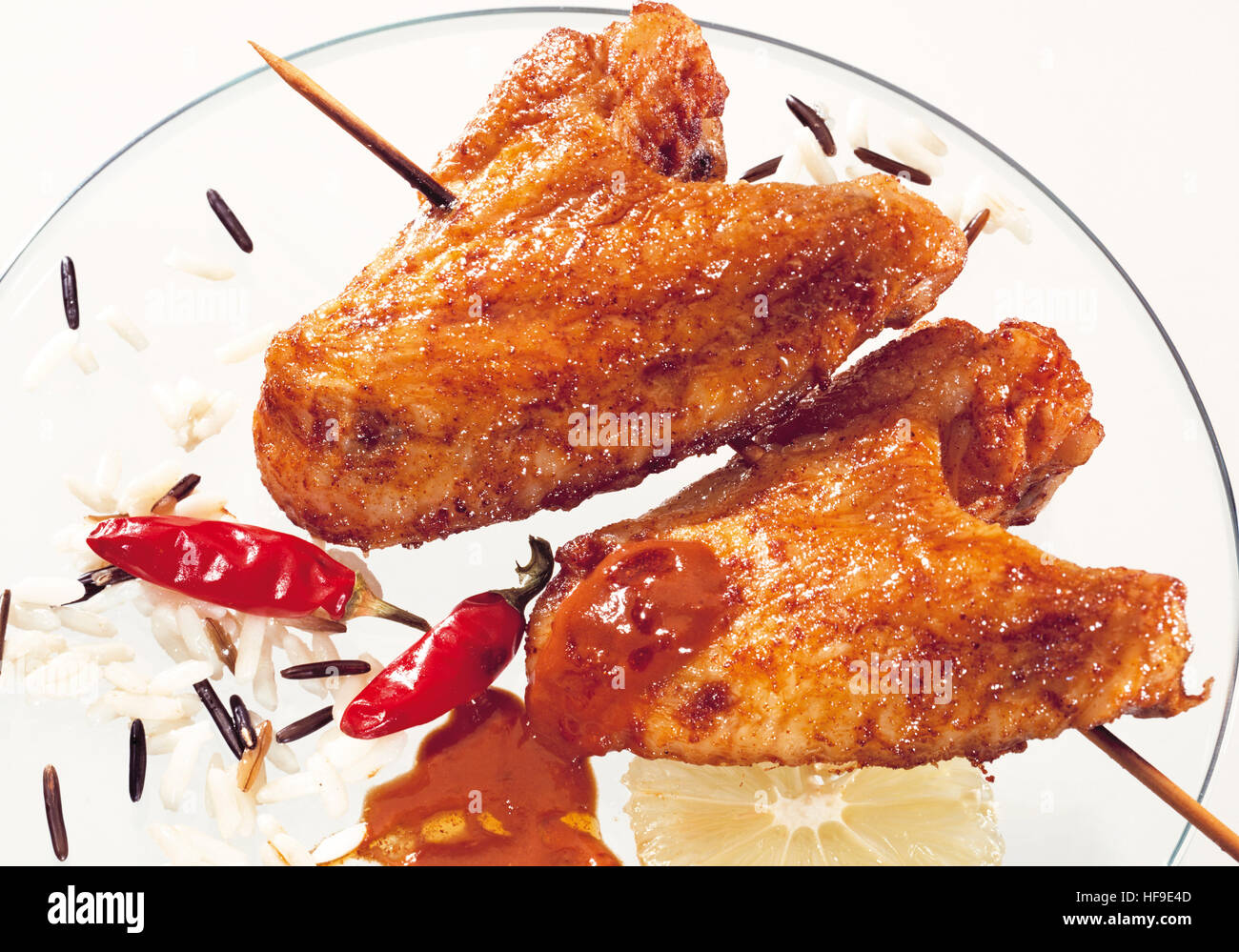Chicken wings on wooden skewer with long grain rice, wild rice, hot