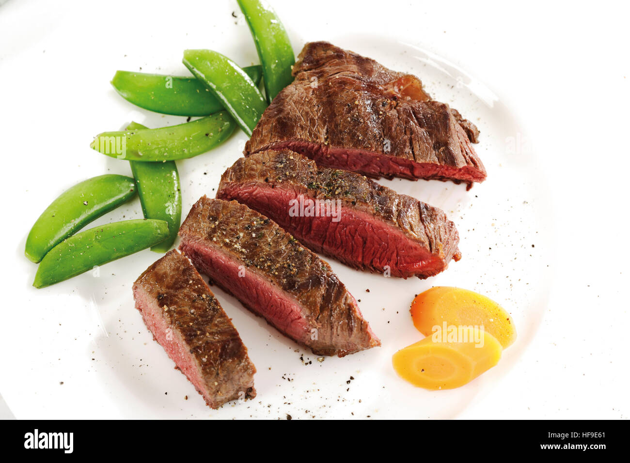 Steak cut into slices with carrots and snow peas Stock Photo