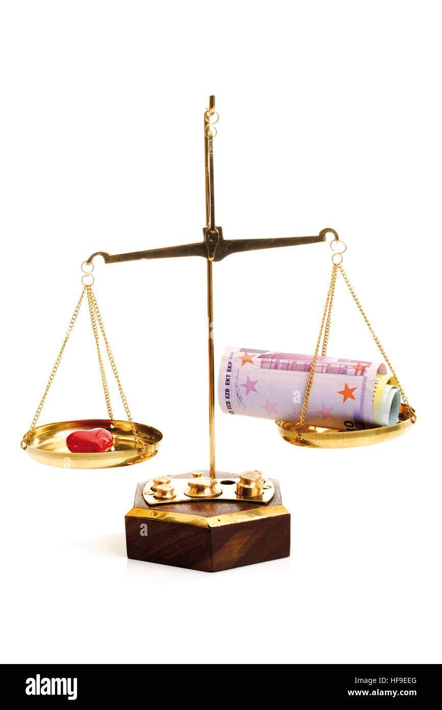 Wad of cash and heart on a balance scale: love or money? Stock Photo