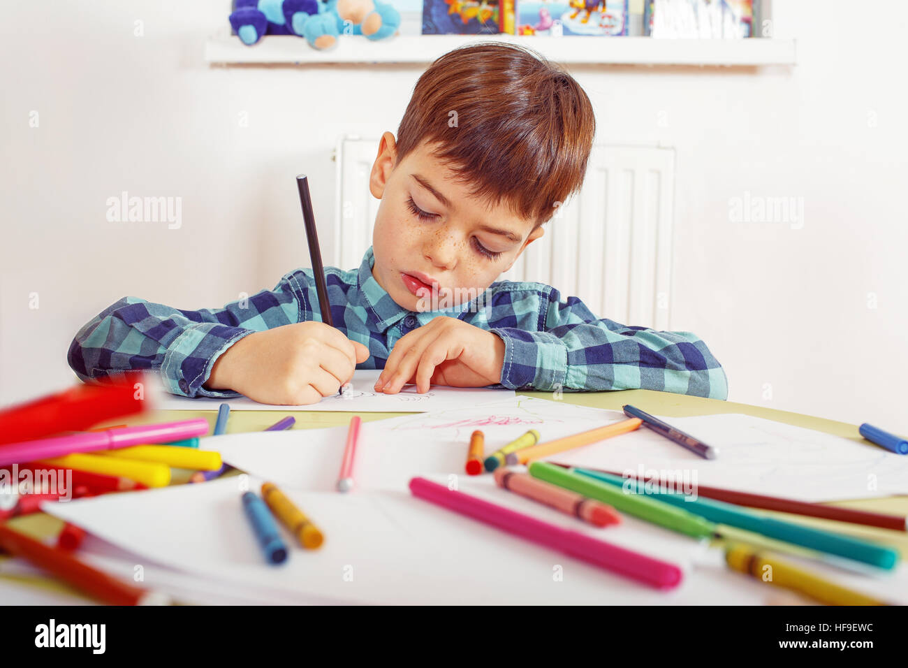 Brown-haired boy in checkered shirt drawing using a pencil Stock Photo -  Alamy
