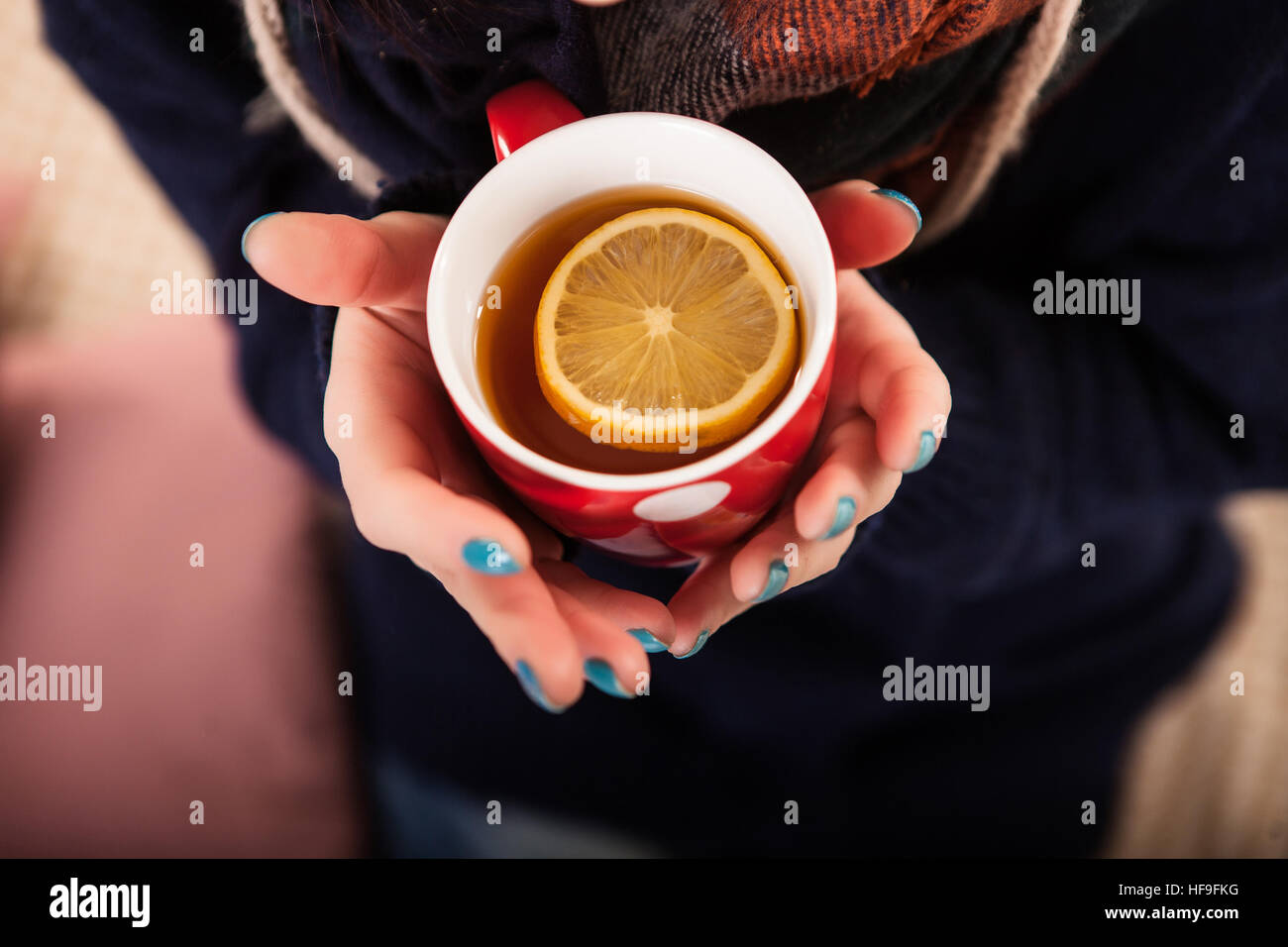 Woman's hand holding cup of tea with lemon on a cold day Stock Photo