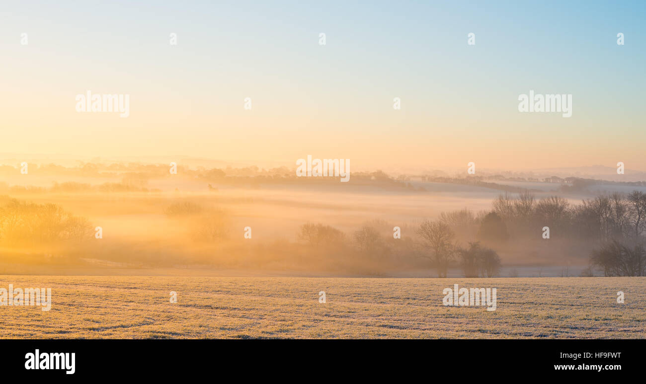 Sun rises over foggy rural countryside on a frosty crisp winters morning with a temperature of -6ºC near Warwick, Warwickshire, UK Stock Photo