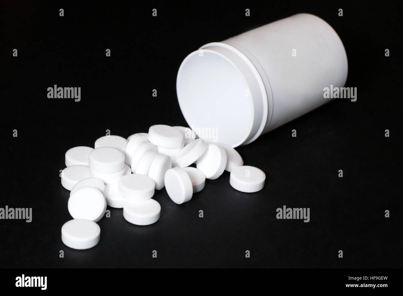 White pills, medicines painkiller. Medications on a black background. Stock Photo