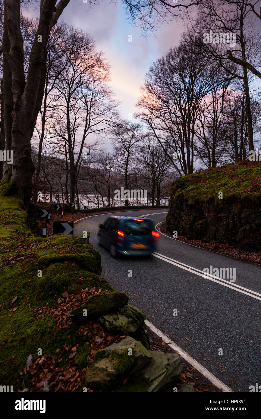 A blue car braking on the bend of the A591 beside Grasmere, in the Lake District, Cumbria Stock Photo