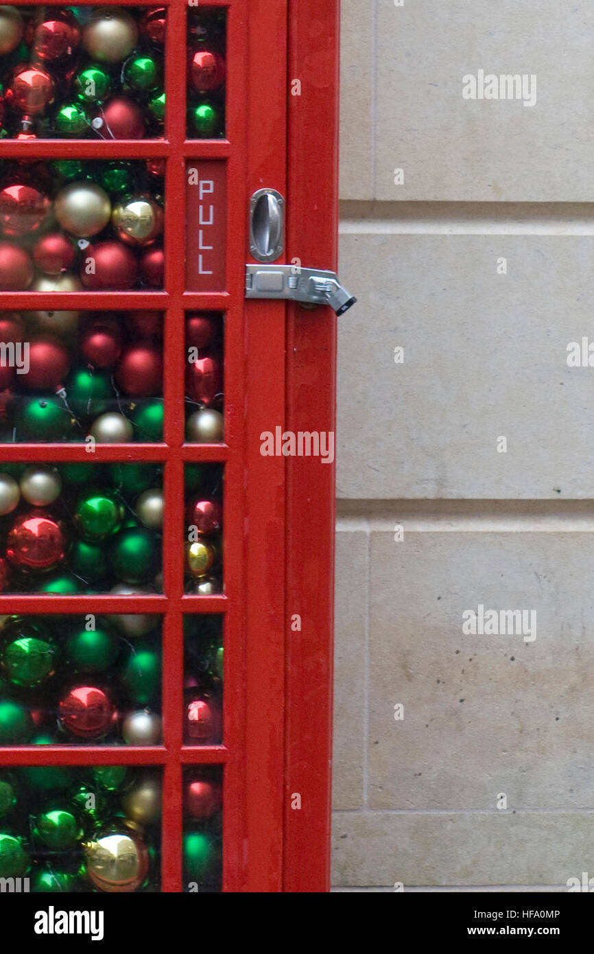 Red Public Telephone Box filled with Christmas Baubles Stock Photo