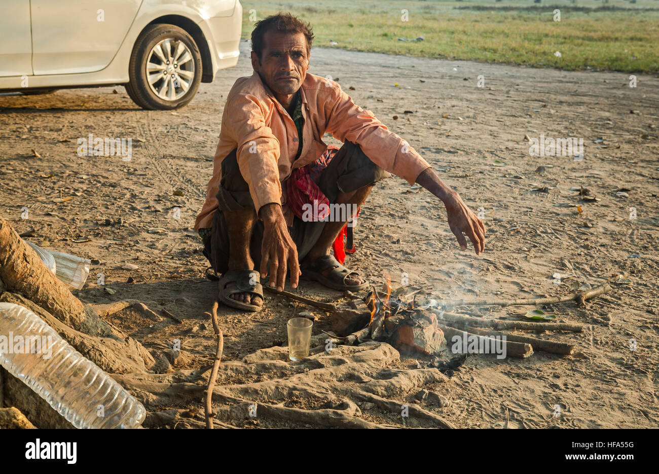 Indian homeless man sits beside a fire to keep warm on a cold winter morning. Stock Photo