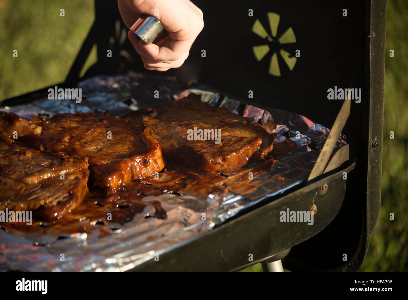 Someone with tongs turning a ribeye steak on a grill Stock Photo ...