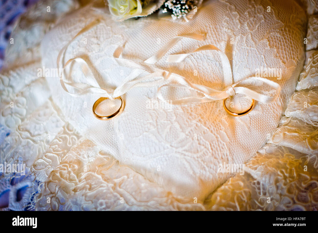 Double gold rings tied on a white pillow white heart-shaped Stock Photo