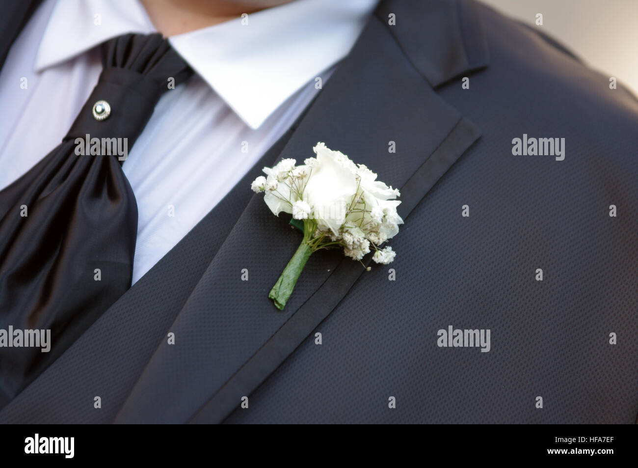 pin with decorative white flowers pinned on the groom's jacket Stock Photo Alamy