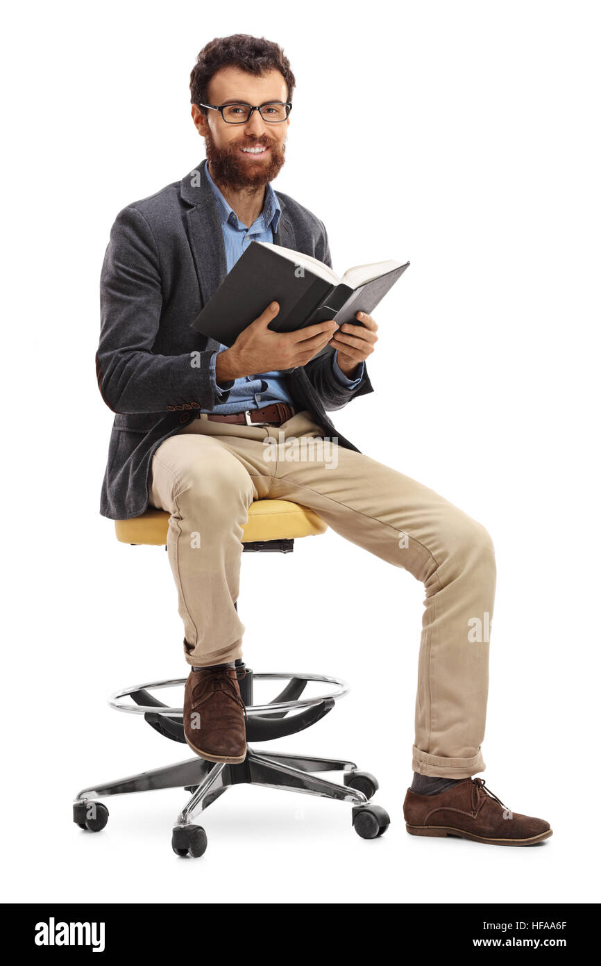Joyful bearded man sitting on a chair and holding a book isolated on white background Stock Photo