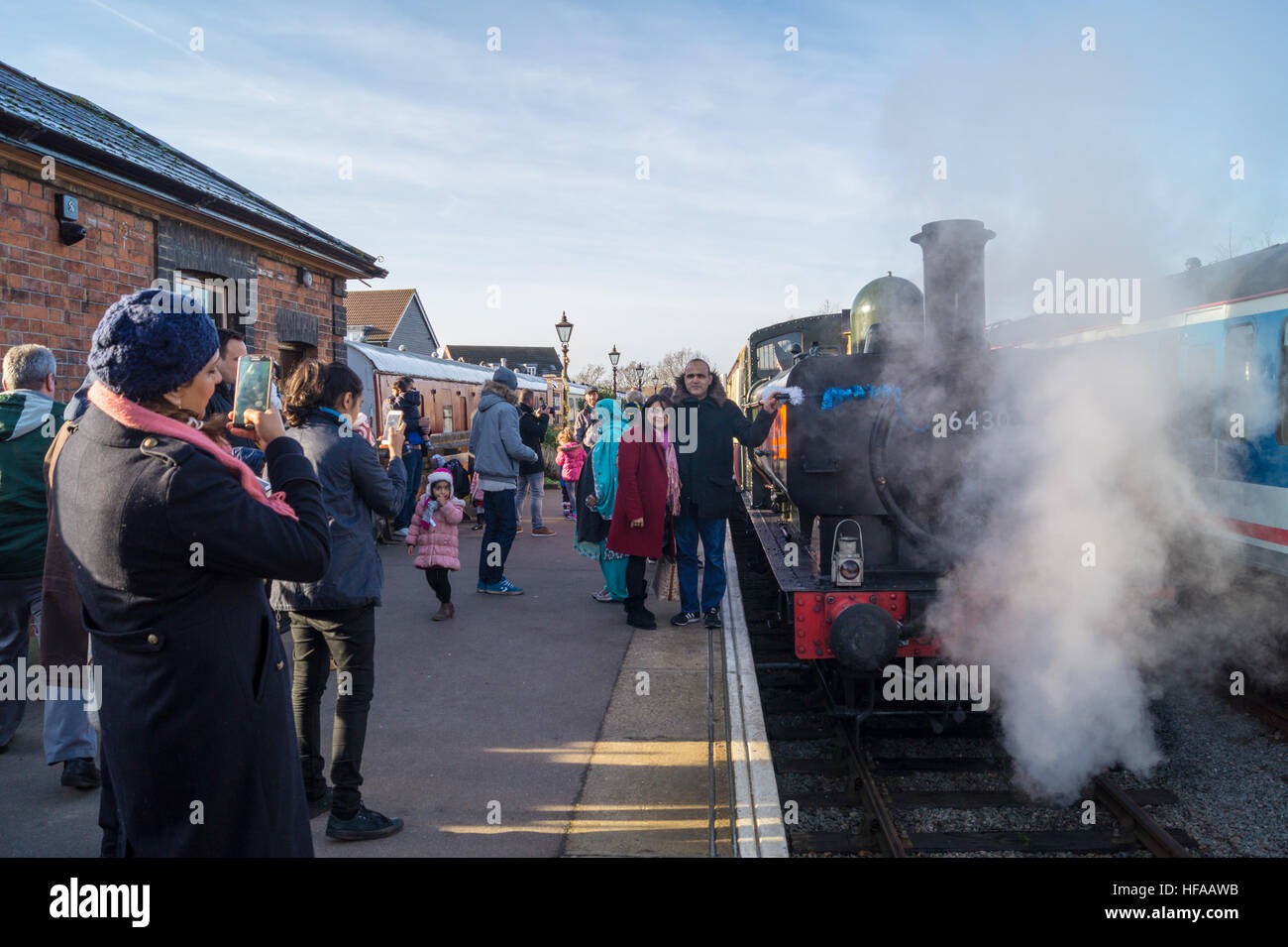Passengers posing for photographs by GWR steam train at Ongar station, Epping Ongar Railway, Essex, England Stock Photo