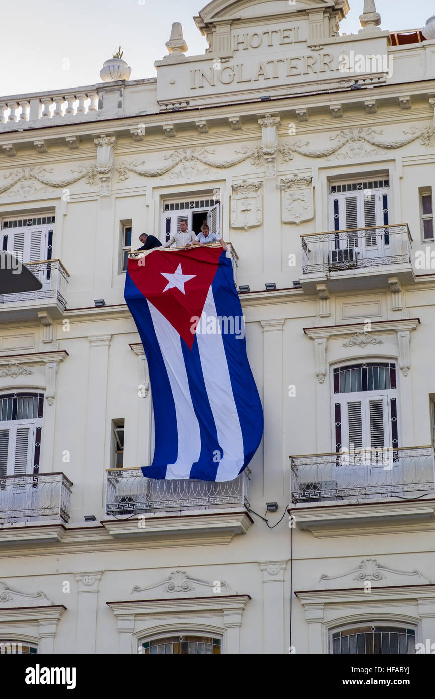 Hanging a giant Cuban flag on the front of the Hotel Inglaterra on the day Fidel Castros death was announced, La Havana, Cuba. Stock Photo