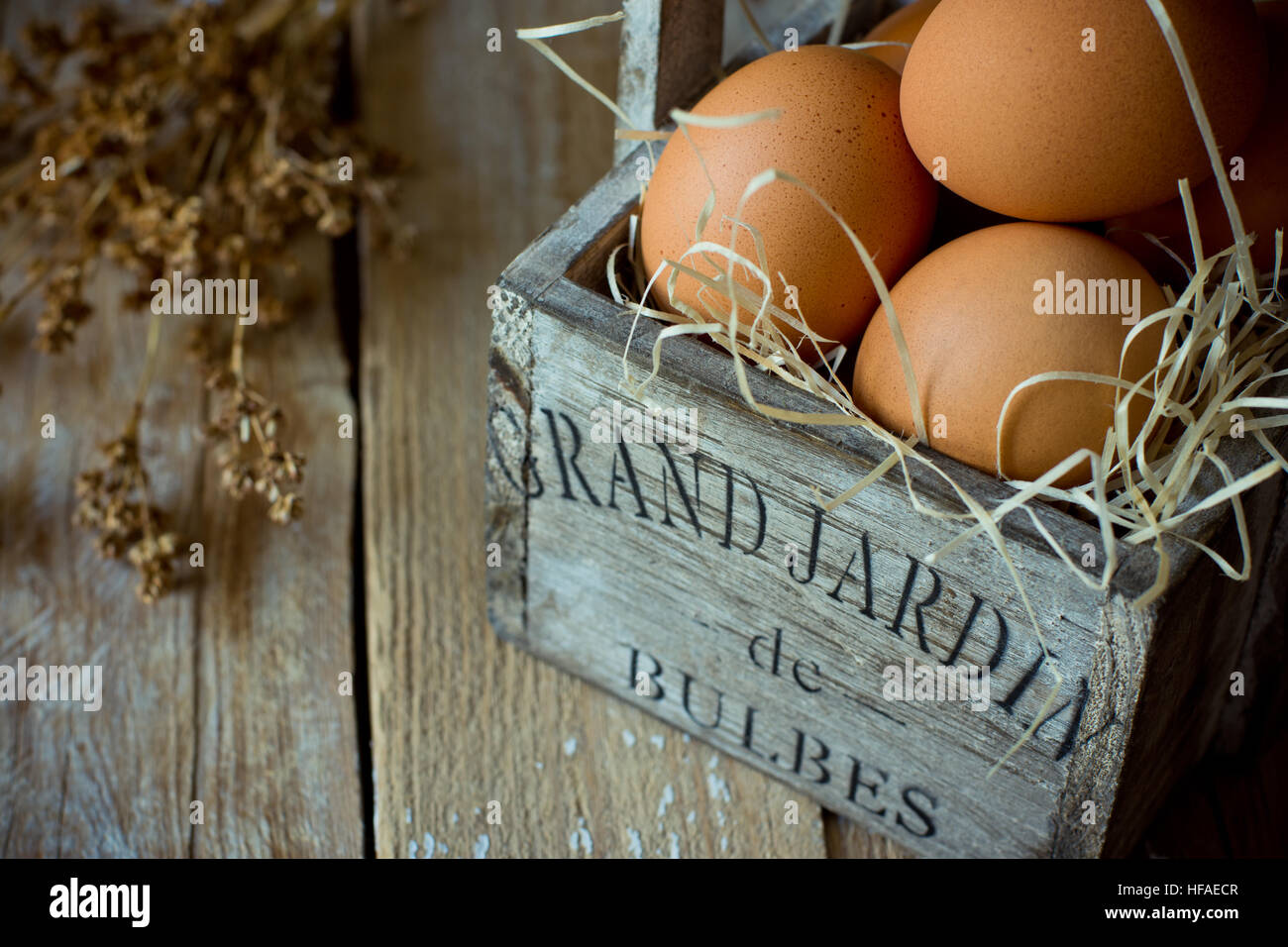 Fresh brown eggs on straw in a vintage shabby chic wood box, dry beige flowers,barn wood background,Easter,kinfolk,minimalistic Stock Photo