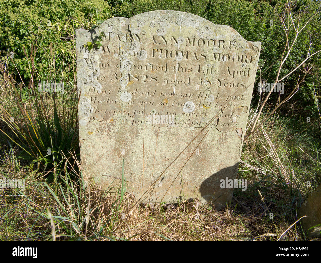 19th century slab sandstone headstone with ornate top and carved dedicated front in rough grass area Stock Photo