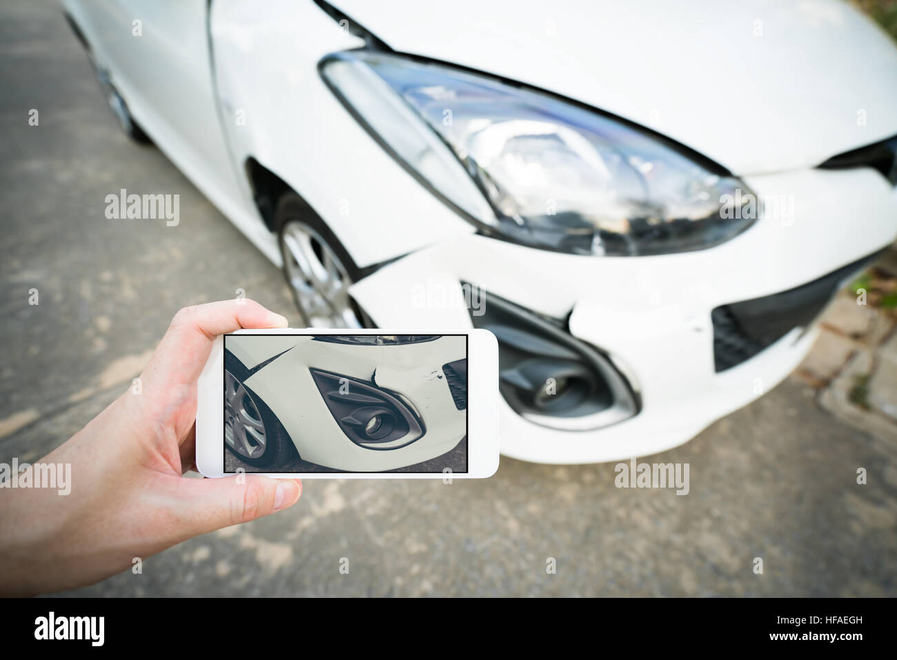 Man taking photo of damaged white car with smartphone Stock Photo