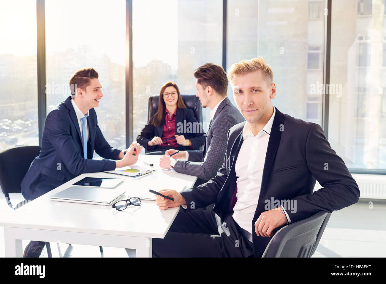 Businessman in suit with colleagues, partners, team at desk  a m Stock Photo