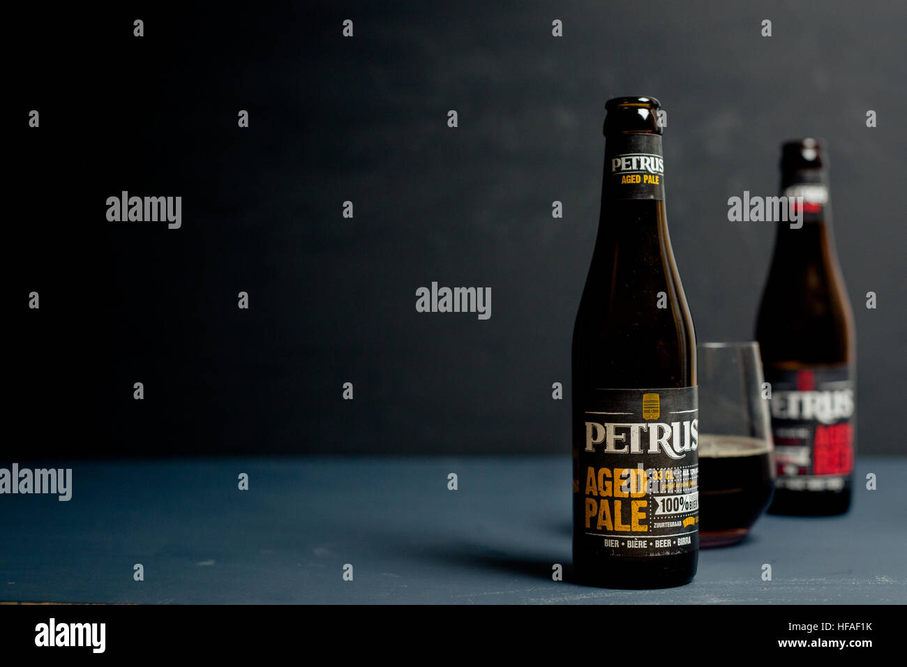 petrus aged red & aged pale bottles with beer in glass against a grey background Stock Photo