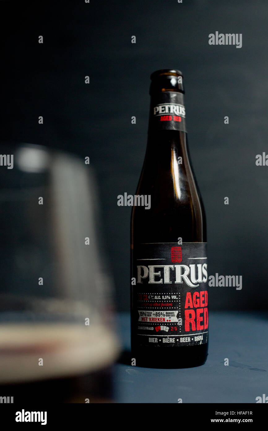 Petrus Aged Red craft ale against a grey background with beer glass Stock Photo