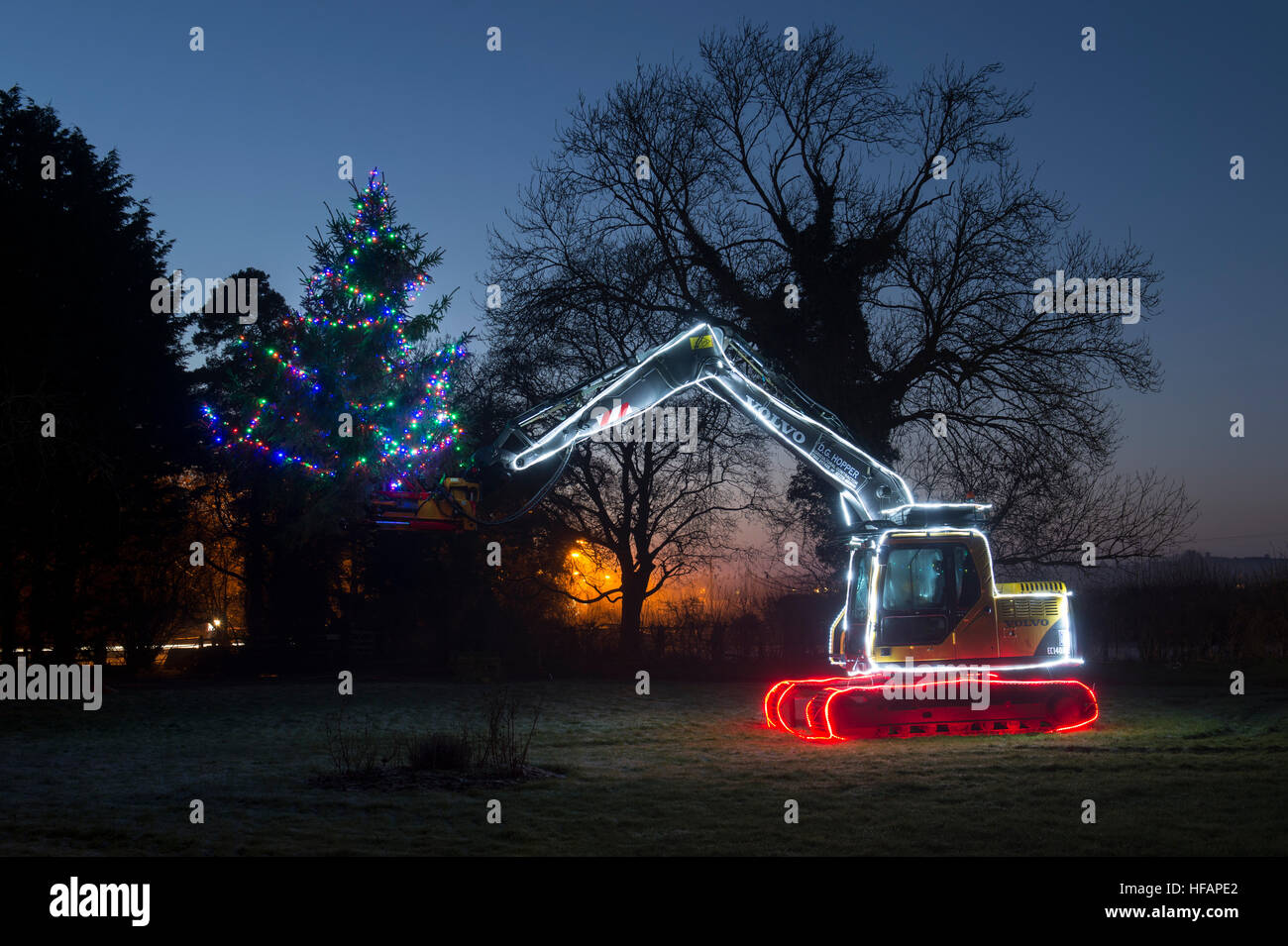 Excavator and Christmas tree with lights decoration at night. Adderbury