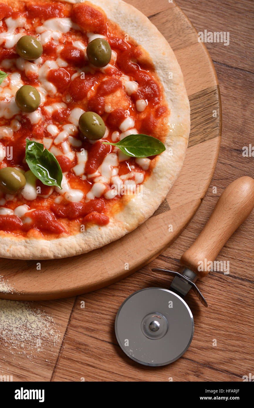 Italian pizza with green olives on cutting board Stock Photo