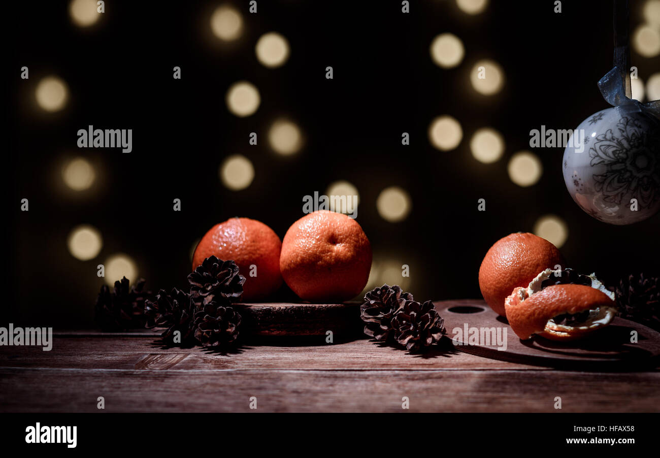 Christmas background - tangerines, cinnamon, bowl, on dark background with bokeh Stock Photo