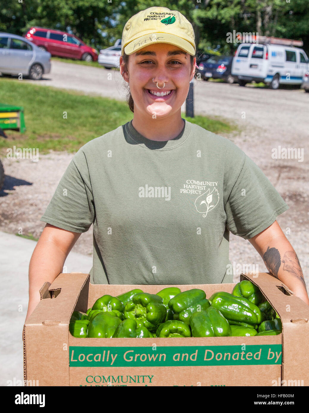 Woman working on a vegetable farm showing the peppers she has just picked. Stock Photo