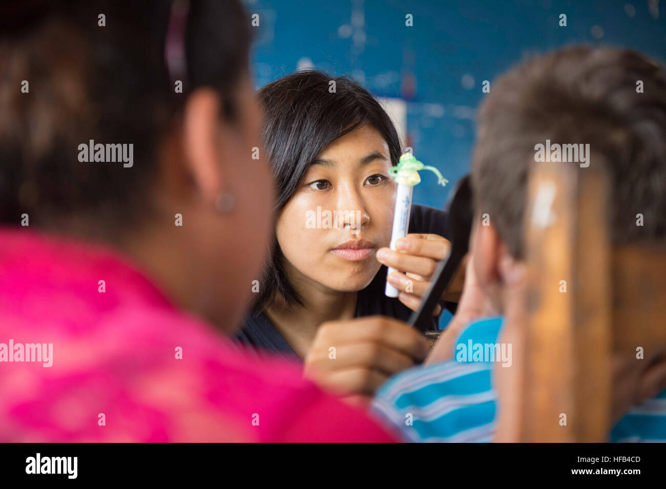 150520-N-AT101-350 PUERTO CABEZAS, Nicaragua (May 20, 2015) - Lt. Serena Leung, a native of Fresno, Calif., and assigned to Naval Hospital Camp Lejeune, N.C., conducts an eye exam on a patient at a medical site set up at Colegio Moravo Juan Amos Comenius during Continuing Promise 2015. Continuing Promise is a U.S. Southern Command-sponsored and U.S. Naval Forces Southern Command/U.S. 4th Fleet-conducted deployment to conduct civil-military operations including humanitarian-civil assistance, subject matter expert exchanges, medical, dental, veterinary and engineering support and disaster respon Stock Photo