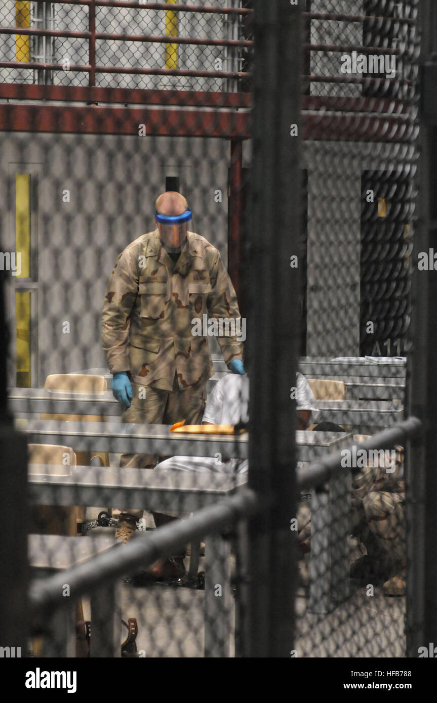 A Sailor assigned to the Navy Expeditionary Guard Battalion assists removal of a soft leg restraint from a detainee as the detainee finishes a class at Joint Task Force Guantanamo. Detainee operations continue at Guantanamo 275562 Stock Photo