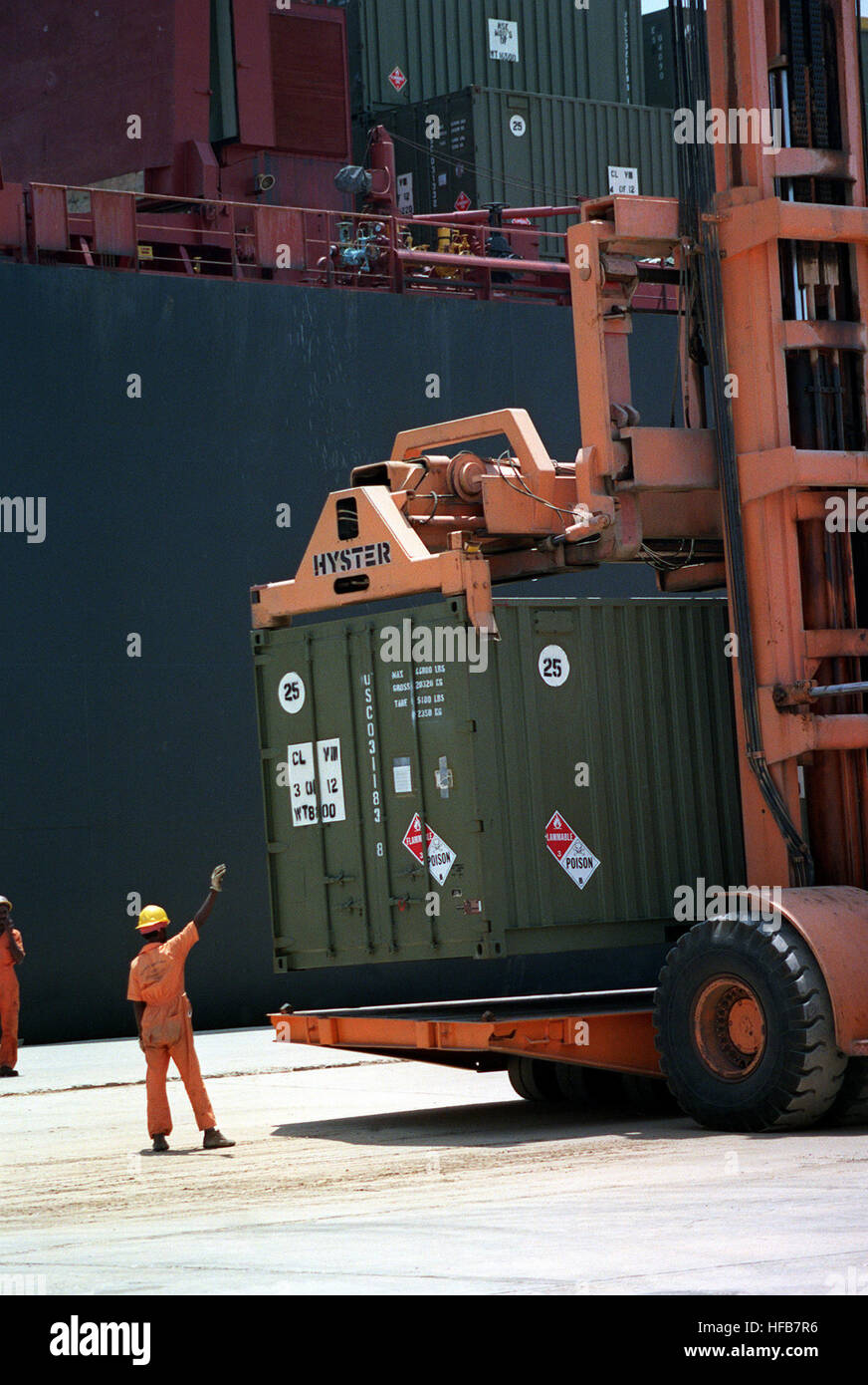 A dock worker guides the operator of a container lift loading a