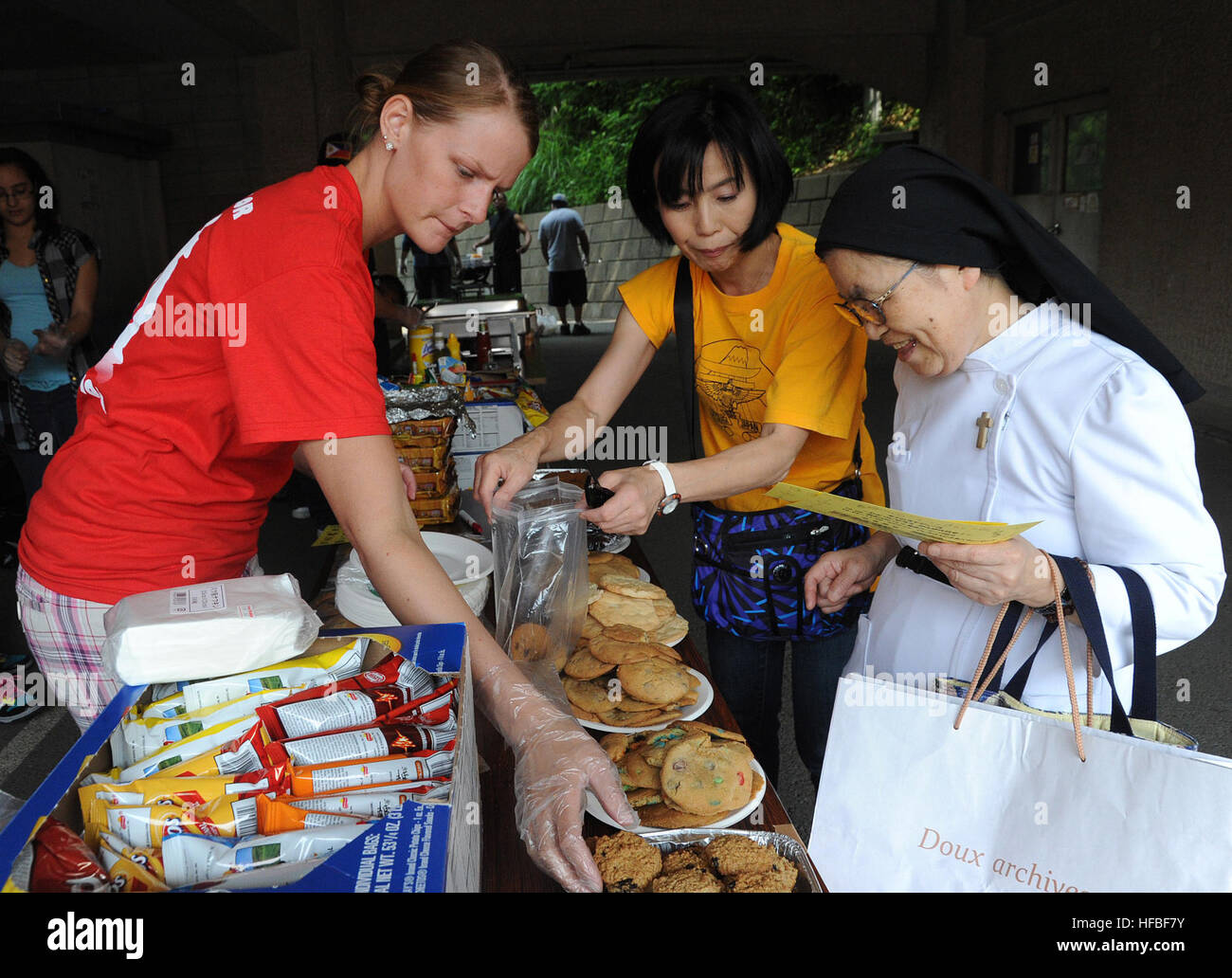 110605-N-VE260-056 FUJISAWA, Japan (June 10, 2011) Aviation Machinist's Mate Airman Heather Wolff, left, and Sumie Maruyama help a nun pick out cookies during the Misono Kodomo-ne-ie Orphanage Festival. Maruyama is from the Host Nation Relations Office at Naval Air Facility Atsugi. This is the second year that Sailors from Naval Air Facility Atsugi volunteered at the event. (U.S. Navy photo by Mass Communication Specialist 2nd Class Justin Smelley/Released)  - Official U.S. Navy Imagery - Aviation Machinist's Mate Airman Heather Wolff helps a nun during the Misono Kodomo-ne-ie Orphanage Festiv Stock Photo