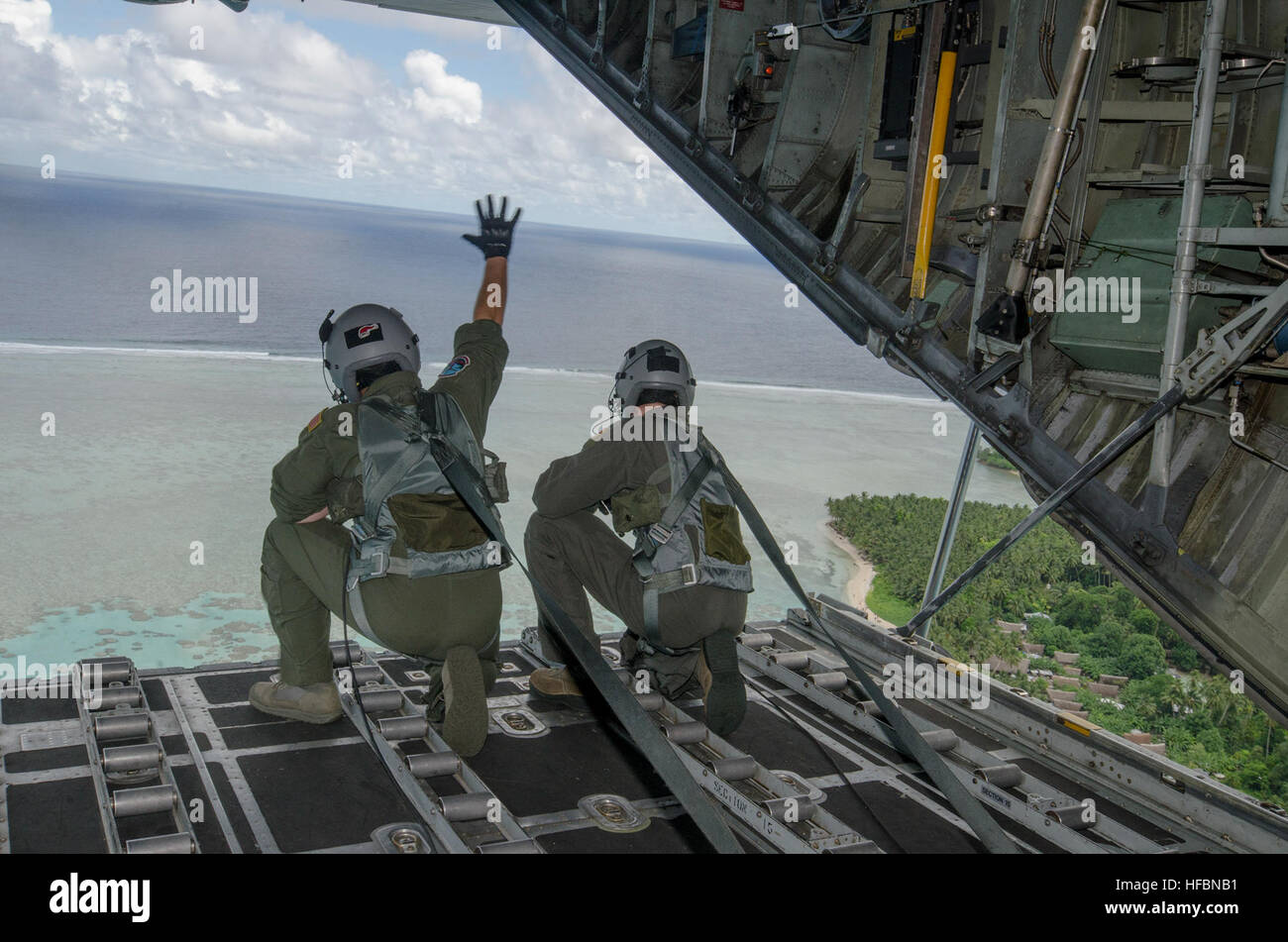 161211-N-YM720-078  FEDERATED STATES OF MICRONESIA (Dec. 12, 2016) – A loadmaster attached to the 36th Airlift Squadron, Yokota Air Base, Japan, waves to the natives of a Micronesian island after dropping off care packages during Operation Christmas Drop, Dec. 11.  Operation Christmas Drop is an international humanitarian operation that provides critical supplies to 56 islands through the Commonwealth of the Northern Marianas, Federated States of Micronesia and Republic of Palau, impacting about 20,000 people. (U.S. Navy photo by Petty Officer 2nd Class Allen Michael McNair/Released) 161211-N- Stock Photo