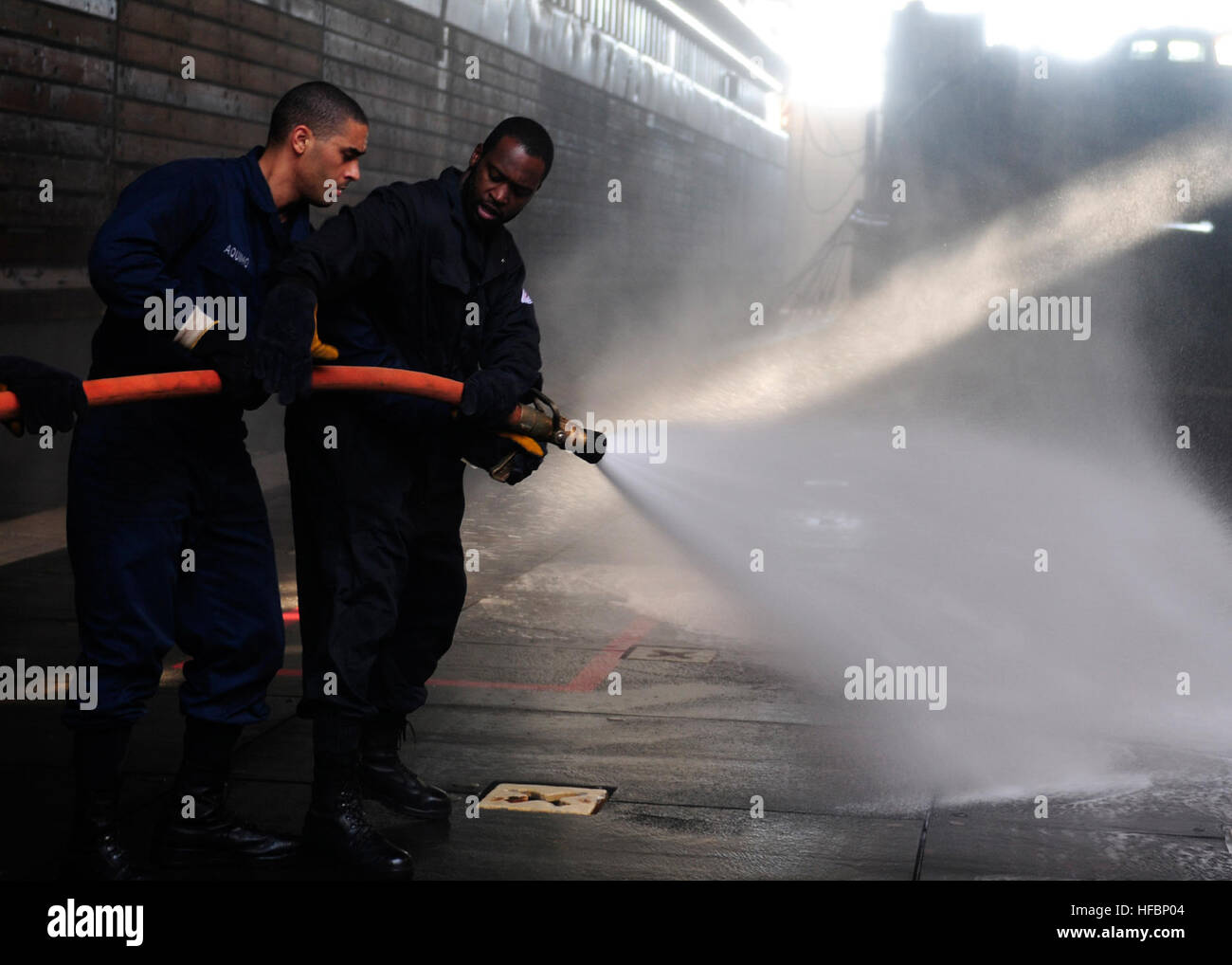 111121-N-WJ771-048 SOUTH CHINA SEA (Nov. 21, 2011) Ð Sailors assigned to the forward-deployed amphibious dock landing ship USS Tortuga (LSD 46) man a fire hose during a crash and salvage drill in the well deck. Tortuga is supporting flood recovery assistance efforts while working closely with the government and military of the Kingdom of Thailand. (U.S. Navy photo by Mass Communication Specialist 2nd Class Casey H. Kyhl/Released)  - Official U.S. Navy Imagery - Sailors train firefighting. Stock Photo