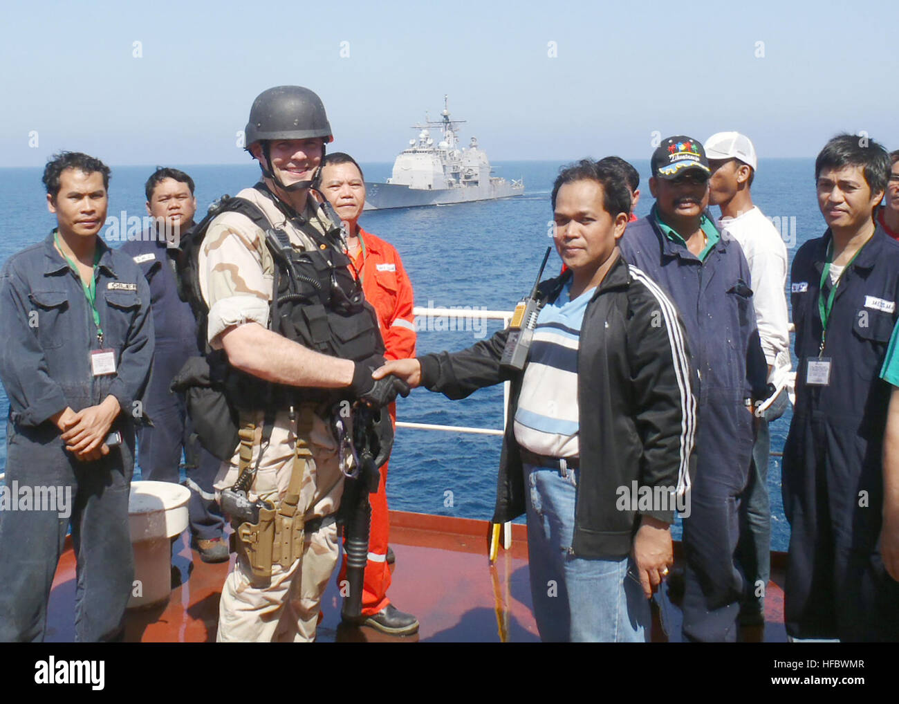 110325-N-BZ392-448 ARABIAN SEA (March 25, 2011) A member of the guided-missile cruiser USS Leyte Gulf (CG 55) visit, board, search and seizure team shakes hands with the master of the Philippine-flagged merchant vessel M/V Falcon Trader II, which had sent out a distress call reporting it had been boarded by pirates. Helicopters from the Leyte Gulf and USS Enterprise (CVN 65) responded to the call and were able to disrupt the attack. Leyte Gulf and Enterprise are supporting Operation Enduring Freedom and regional maritime security operations as part of their deployment to the U.S. 5th Fleet are Stock Photo