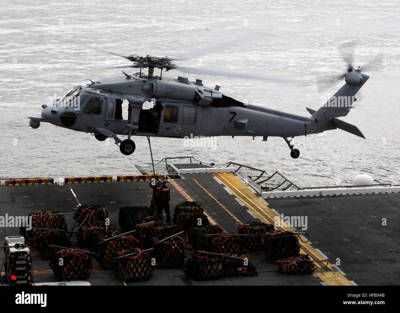 Sailors aboard the amphibious assault ship USS Peleliu (LHA 5) attach a ...