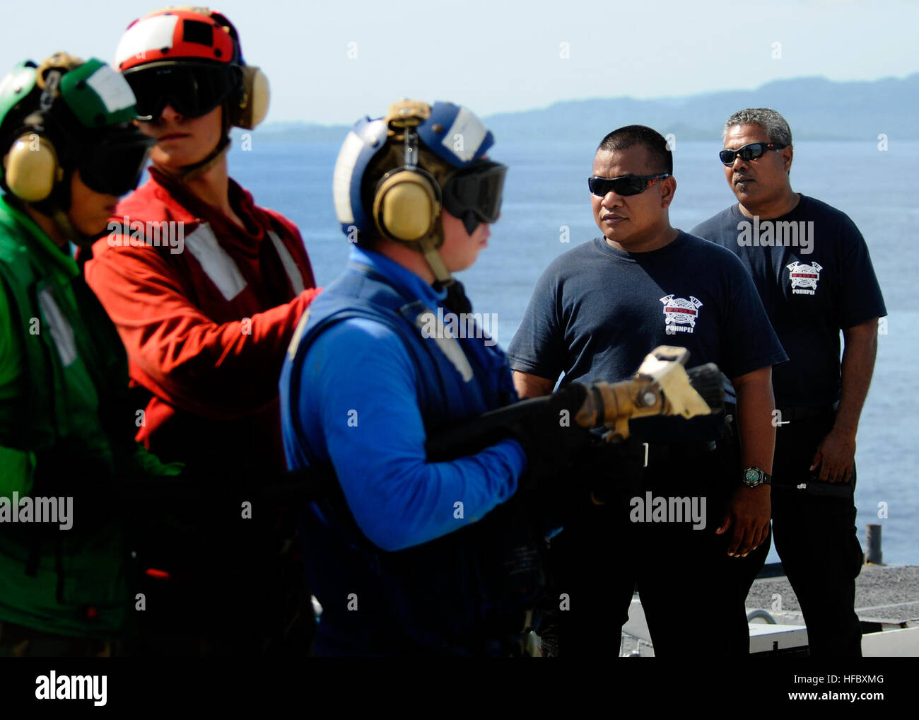 Firefighters from the Pohnpei Airport Fire and Rescue of the Federated States of Micronesia Whyselle Moses and Maxi Elias observe a flight deck firefighting drill during a subject matter expert exchange aboard the amphibious transport dock ship USS Cleveland off the shores of Pohnpei during Pacific Partnership 2011. Pacific Partnership is a five-month humanitarian assistance initiative that that will make port visits to Tonga, Vanuatu, Papua New Guinea, Timor Leste, and the Federated States of Micronesia. (Photo by: Petty Officer 1st Class Eli J. Medellin) Flight deck firefighting training abo Stock Photo