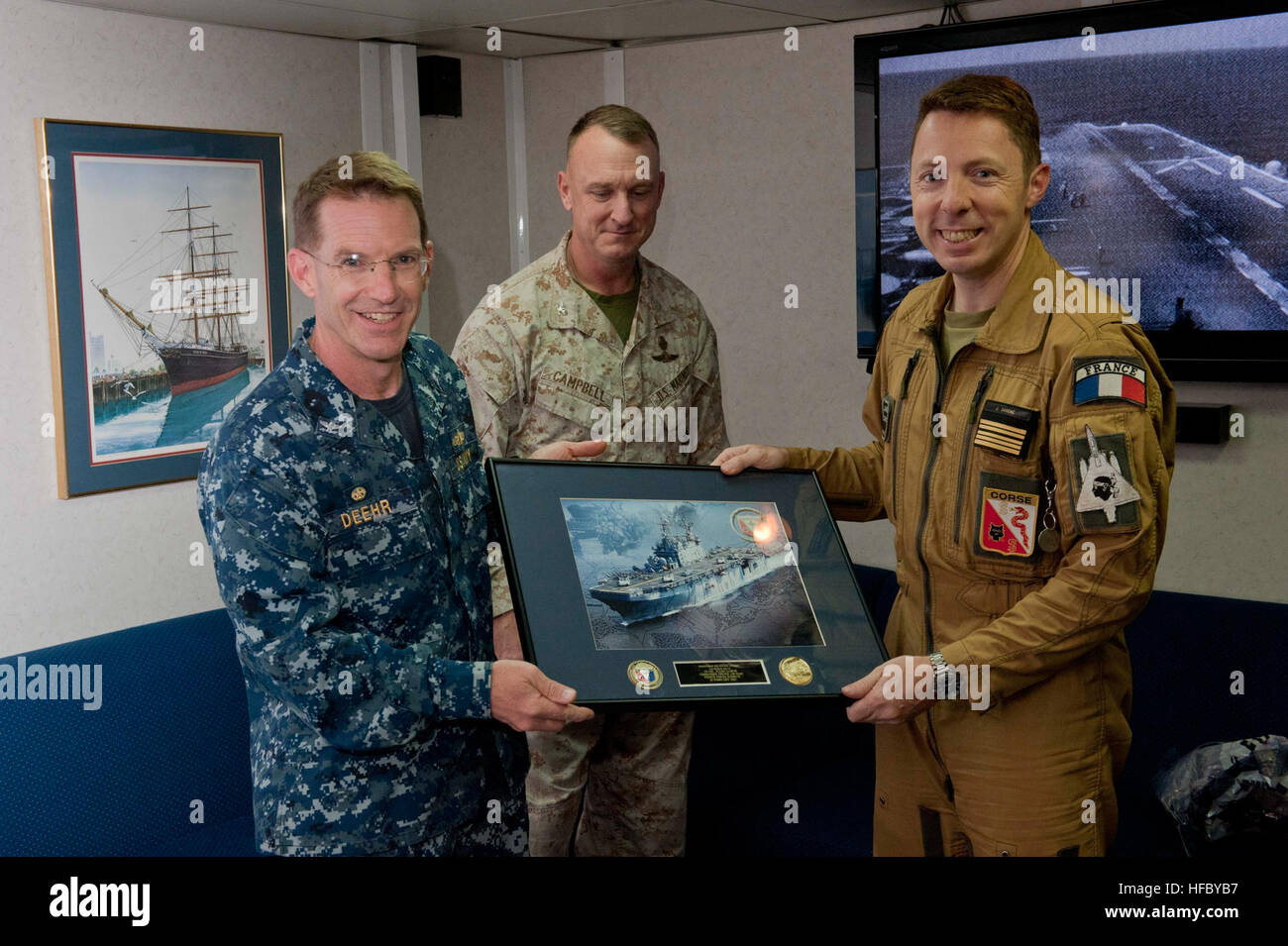 Capt. John D. Deehr, left, commanding officer, amphibious assault ship USS Peleliu (LHA 5), and Col. Scott Campbell, center, commanding officer, 5th Marine Expeditionary Unit, present a gift to Col. Julien Sabéné, commanding officer, French Air Base French, Forces-Djibouti, during his visit. Peleliu is the flagship for the Peleliu Amphibious Ready Group and is deployed with the embarked 15th Marine Expeditionary Unit in support of maritime security operations and theater security cooperation efforts in the U.S. 5th Fleet area of responsibility. (U.S. Navy photo by Mass Communication Specialist Stock Photo