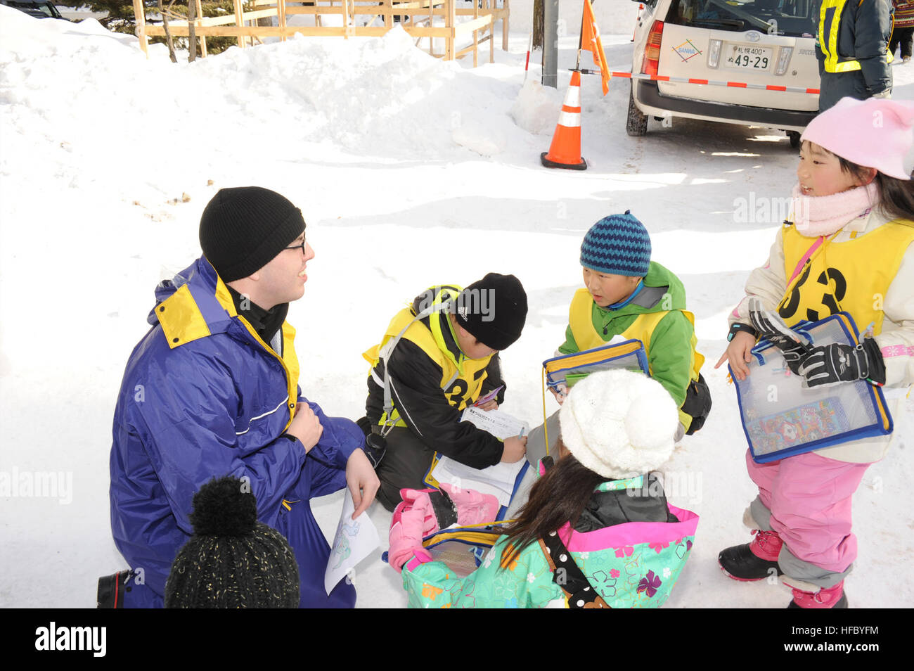 Operations Specialist 3rd Class Ryan Hershiser, assigned to Commander, Task Force 72, from Columbus, Ohio, speaks with Japanese elementary school children about the USS Constitution snow sculpture during the 66th Annual Sapporo Snow Festival. Hershiser is a member of the 2015 Navy Misawa Snow Team who created the sculpture for the festival and as a tribute to the U.S. Navy's oldest commissioned ship. This is the 32nd year that Naval Air Facility Misawa and its tenant commands have sent a delegation of Sailors to the festival to create a sculpture, and to serve as goodwill ambassadors. (U.S. Na Stock Photo