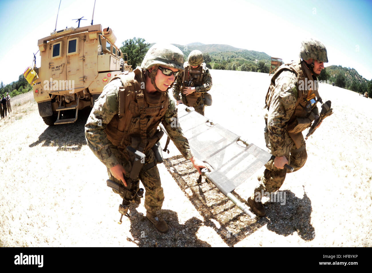 A combat litter team riding in a convoy from Naval Mobile Construction  Battalion 3 runs to transport mock casualties during a simulated helicopter  medical evacuation scenario. NMCB 3 is conducting their final