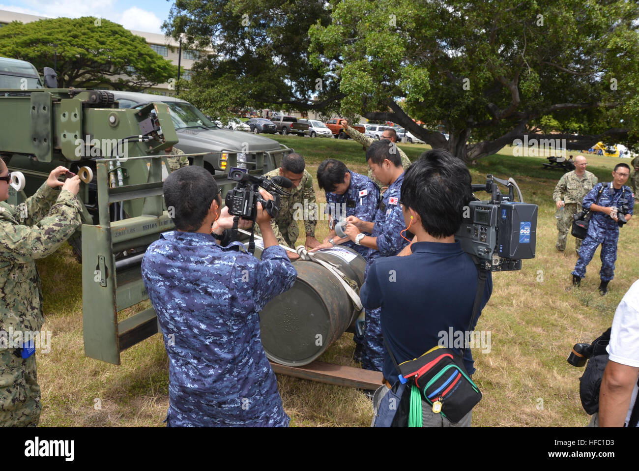 Members of the Japan Maritime Self-Defense Force (JMSDF) and civilian media document U.S. Navy reserve Logistics Specialist 2nd Class Shamshi Lalji, assigned to Navy Cargo Handling Battalion (NCHB) 14, and officers from the JMSDF label drums of water delivered during the Humanitarian Assistance/Disaster Relief (HA/DR) portion of Rim of the Pacific (RIMPAC) Exercise 2014. Twenty-two nations, more than 40 ships and six submarines, more than 200 aircraft and 25,000 personnel are participating in RIMPAC from June 26 to Aug. 1, in and around the Hawaiian Islands. The world's largest international m Stock Photo