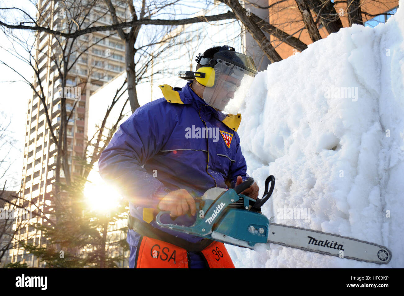 Chief Builder Billy Harger, assigned to Public Works Department Misawa, from Pearl City, Hawaii, uses a chainsaw to shape a portion of the USS Constitution snow sculpture during the 66th Annual Sapporo Snow Festival. Harger is captain of the 2015 Navy Misawa Snow Team who are creating the sculpture for the festival and as a tribute to the U.S. Navy's oldest commissioned ship. This is the 32nd year that Naval Air Facility Misawa and its tenant commands have sent a delegation of Sailors to the festival to create a sculpture, and to serve as goodwill ambassadors. (U.S. Navy photo by Senior Chief  Stock Photo