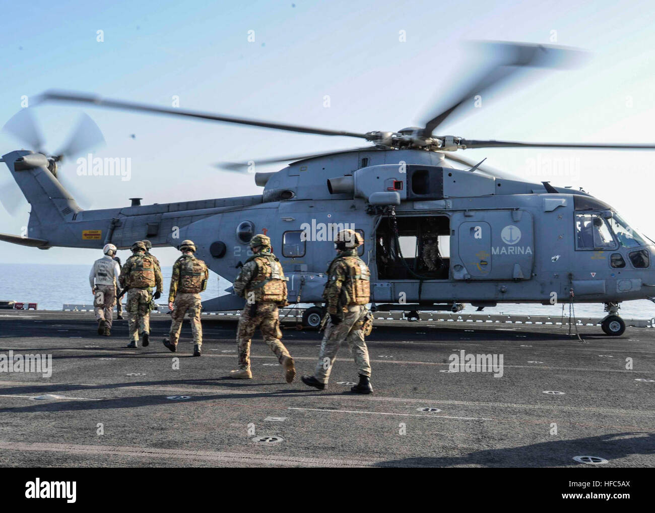 Italian Marines embark an EH-101 Merlin helicopter on the flight deck aboard the amphibious assault ship USS Boxer (LHD 4). Boxer is the flagship for the Boxer Amphibious Ready Group and, with the embarked 13th Marine Expeditionary Unit, is deployed in support of maritime security operations and theater security cooperation efforts in the U.S. 5th Fleet area of responsibility. (U.S. Navy photo by Mass Communication Specialist 3rd Class J. Michael Schwartz/Released) Italian Navy-Marine interaction 131219-N-QP351-123 Stock Photo