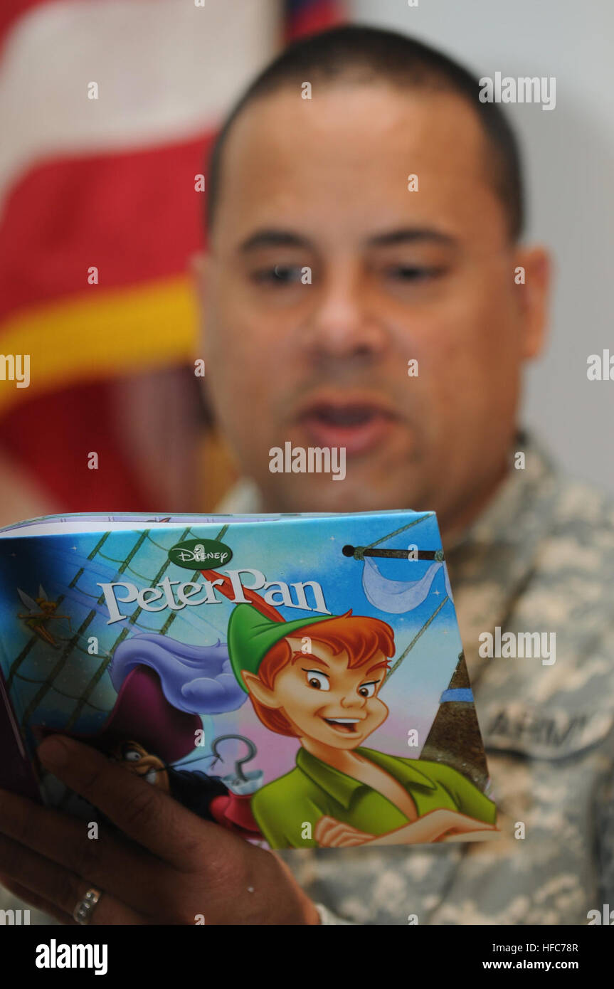 U.S. Army Sgt. Nazario Castro, attached to Joint Detention Group Joint Task Force Guantanamo, reads a Peter Pan book to his two sons while being recorded as part of the United Through Reading program, at the Trooper Chapel on Guantanamo Bay, April 4. The program sponsors books to service members, and also provides the video to be sent to the member’s family while they are deployed. JTF GTMO troops parent from afar 110404-N-AT101-027 Stock Photo