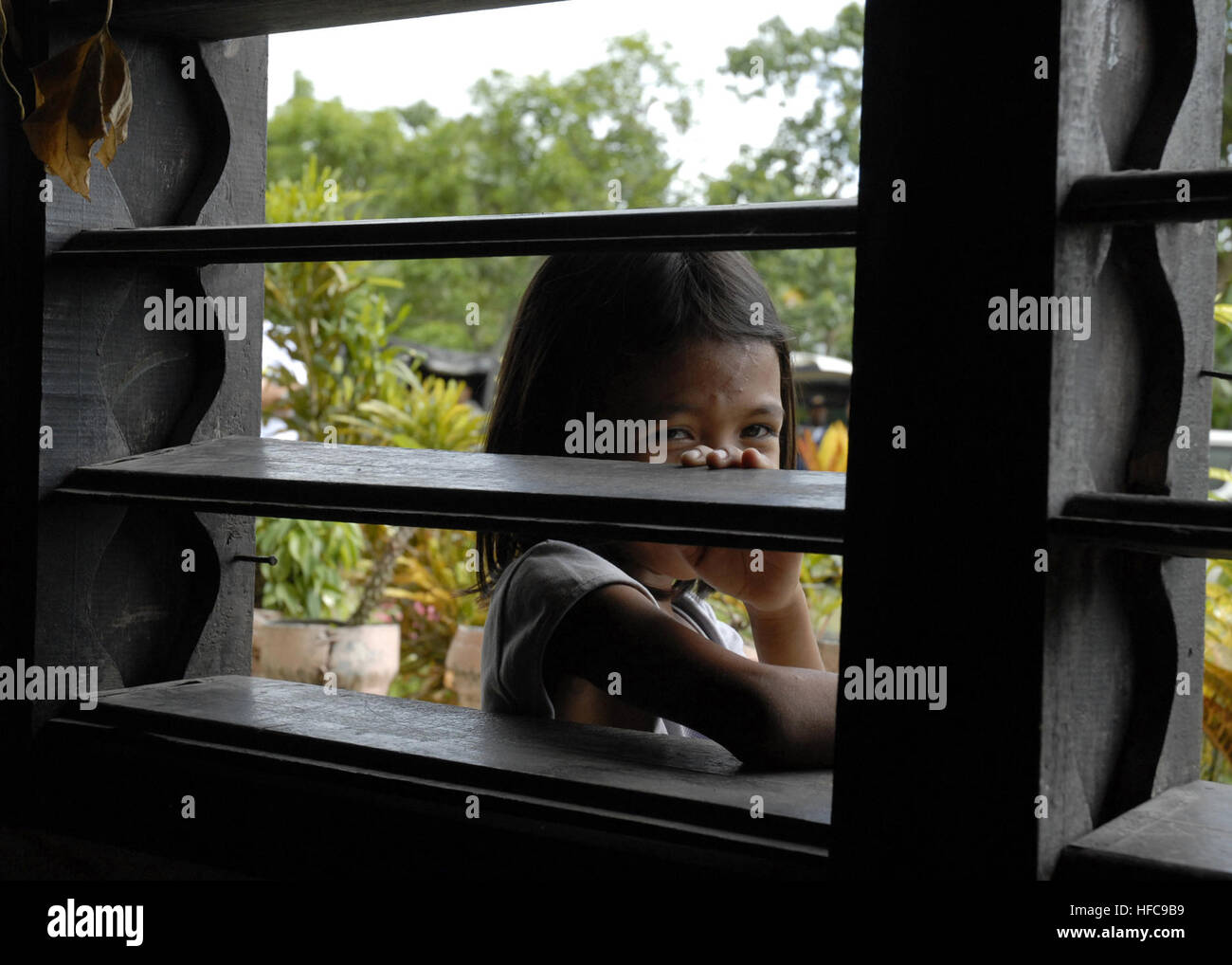 A Filipino child looks through the window of a school that will be remodeled with the cooperation from members of the Filipino 54th Engineering Brigade, Naval Mobile Construction Battalion (NMCB) 7, and Amphibious Construction Battalion (ACB) 1 in Cotabato, Philippines, June 16. NMCB-7 and ACB-1 are deployed with amphibious assault ship USS Peleliu (LHA 5) in support of Pacific Partnership 2007, a four-month humanitarian assistance mission to Southeast Asia and Oceania that includes specialized medical care and various construction and engineering projects. Local Child Observes Future Humanita Stock Photo
