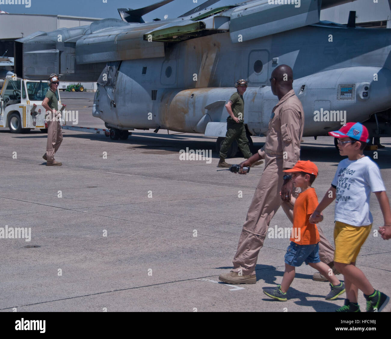 U.S. Marine Corps Capt. Kwabena Okyereboaten, Special-Purpose Marine Air-Ground Task Force Crisis Response air maintenance officer, leads students from the Belpasso Madre Teresa di Calcutta school around an MV-22B Osprey at Naval Air Station Sigonella, Italy, June 18, 2013. The students toured NAS Sigonella and thanked the Marines and Sailors from Special-Purpose MAGTFs Africa and Crisis Response for moving and delivering more than 650 boxes of paper from the Navy Exchange Depot to the elementary school last month as part of the NAS Sigonella community relations initiative. (U.S. Navy photo by Stock Photo