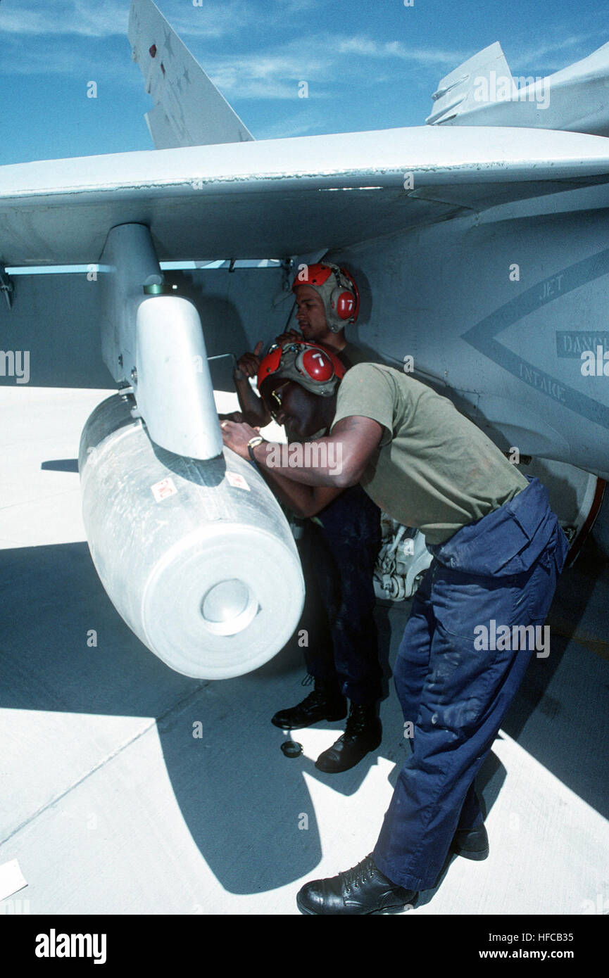 Sgt. Jamal G. Walker and Lance Cpl. Carl Feaster tighten the sway braces on a Mark 77 napalm bomb while loading it onto the wing pylon of a Marine Strike Fighter Squadron 321 (VMHA-321) F/A-18A Hornet aircraft.  The reserve squadron is at Fallon for two weeks of active duty training at the Naval Air Warfare Center target complex. Mark 77 bomb loaded on FA-18 Stock Photo