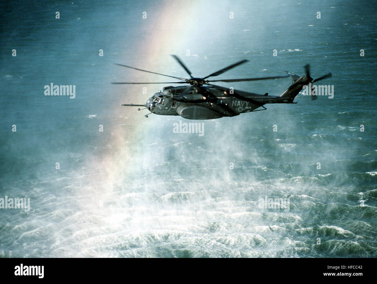 A rainbow is formed in the mist rising from the ocean as a Helicopter Mine Countermeasures Squadron 15 (HM-15) MH-53E Sea Dragon helicopter conducts mine countermeasures operations near Naval Air Station, Alameda, Calif. MH-53E Sea Dragon rainbow Stock Photo