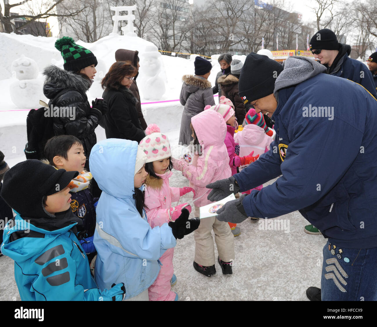 Petty Officer 2nd Class Tywan Ballard, an aviation electronics technician,  hands out Manga comic books to children attending the 62nd Annual Sapporo Snow Festival. Ballard and other members of the Misawa Navy Snow Team are in Sapporo representing their commands at Naval Air Facility Misawa, Japan. This is the 28th year the base sent a team to the northern Japanese city to create a snow sculpture and interact with the local populace. The Mangas commemorate the 50th Anniversary of the Treaty of Mutual Cooperation and Security between the United States and Japan. Misawa Navy Snow Team Meet with  Stock Photo