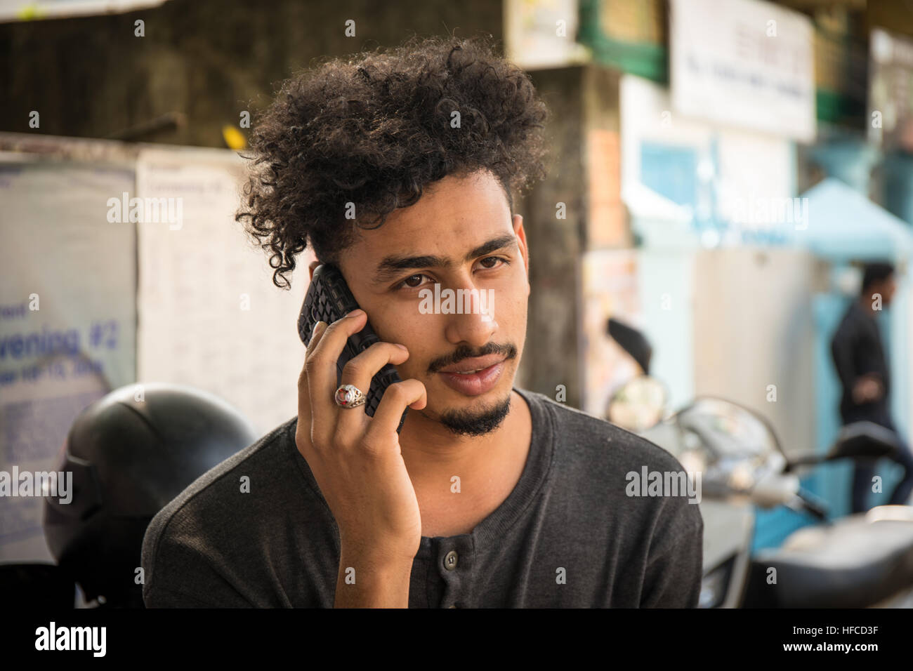 Handsome and attractive young Indian man with black fashionable curly hair  and a black tshirt is talking on the phone Stock Photo - Alamy